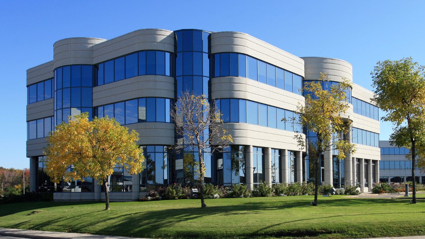Modern glass-and-stone commercial office building on a landscaped lot