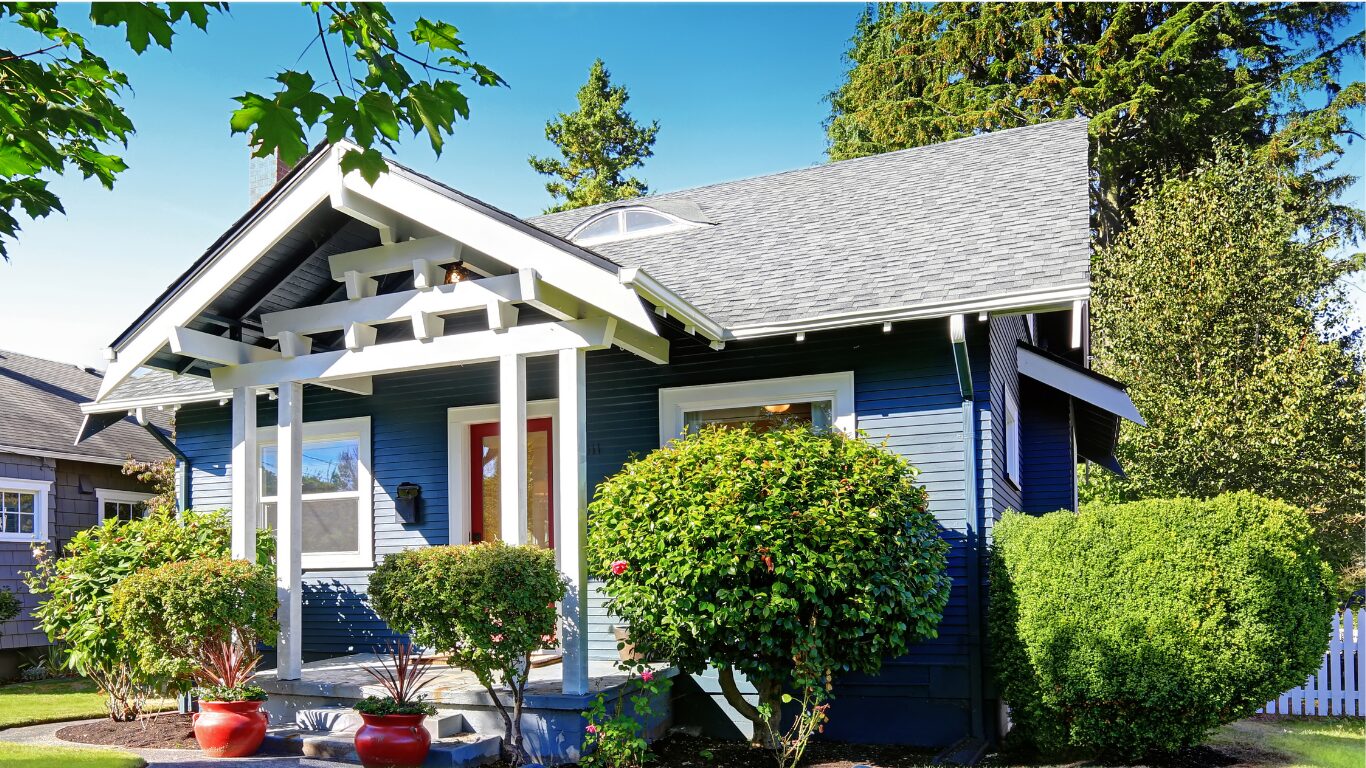 Blue craftsman-style home with a covered front porch and mature landscaping