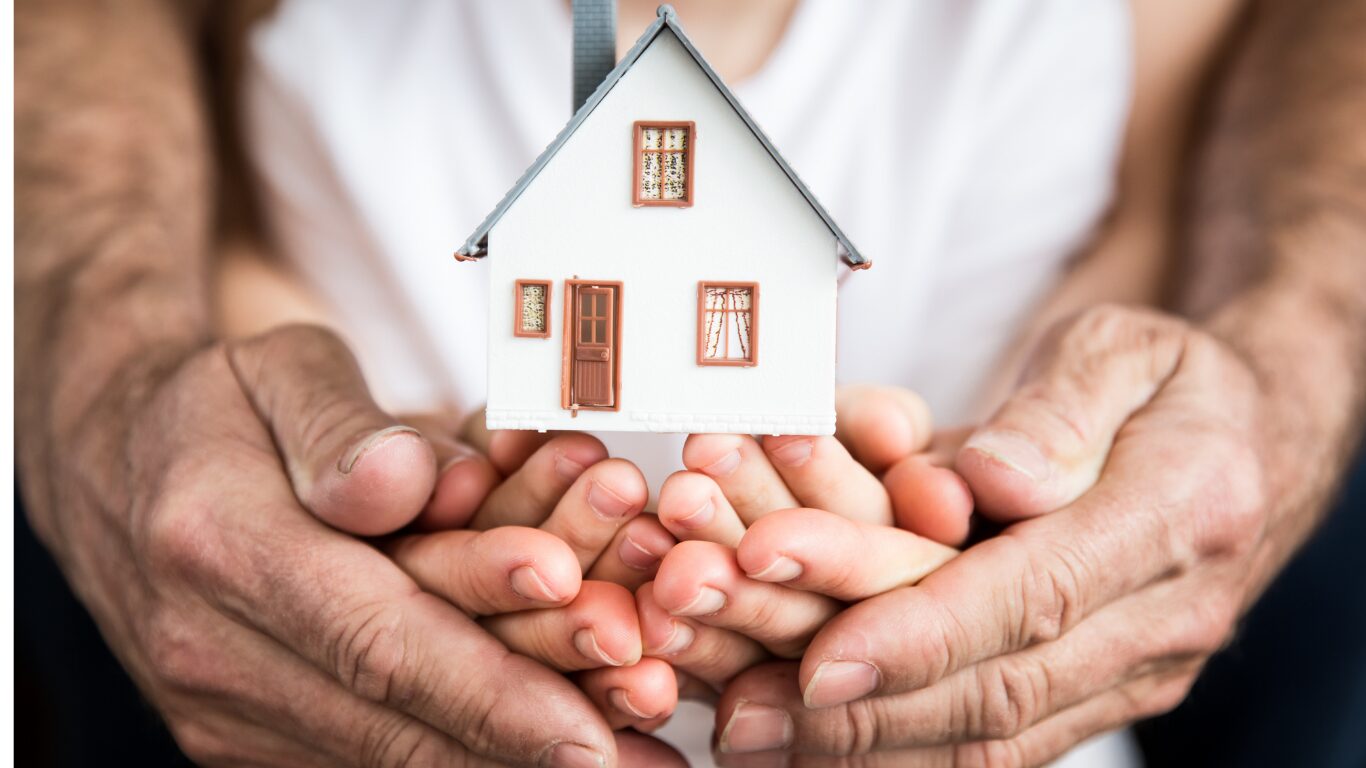 Family hands cradling a small model house